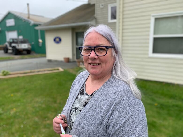 A woman with white hair stands in front of a building. The woman is Lori Edgar, the operations manager at Affirmative House, an affordable housing development in Dartmouth, Nova Scotia. 