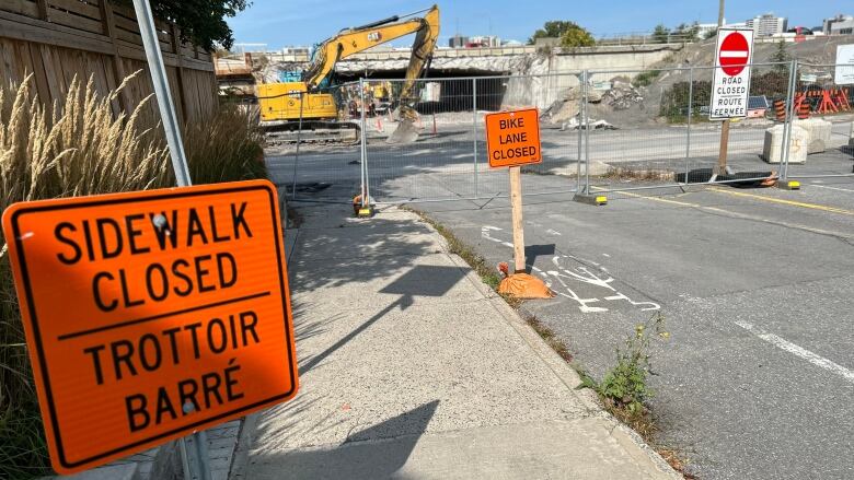 Orange signs block a street under construction in early autumn.