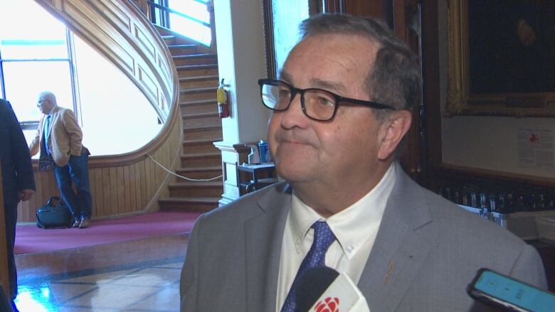 A man in a suit with a CBC-branded mic being pointed at him