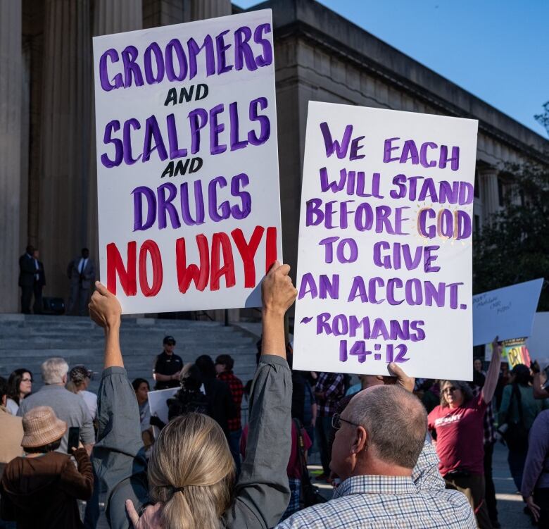 Protesters hold placards during a rally against gender-affirming care in Nashville, Tennessee at the War Memorial Plaza on October 21,2022. (Photo by SETH HERALD / AFP) (Photo by SETH HERALD/AFP via Getty Images)