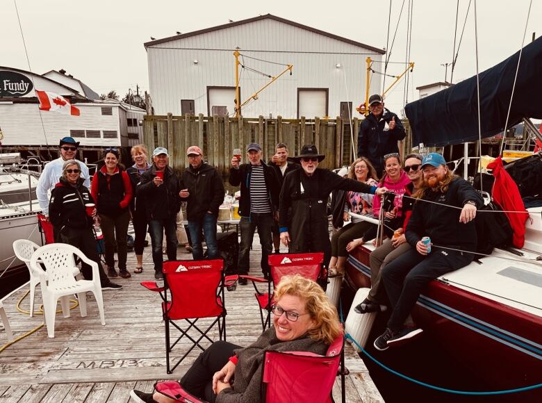 A group of sailors socialize on the dock after a sailing race. 