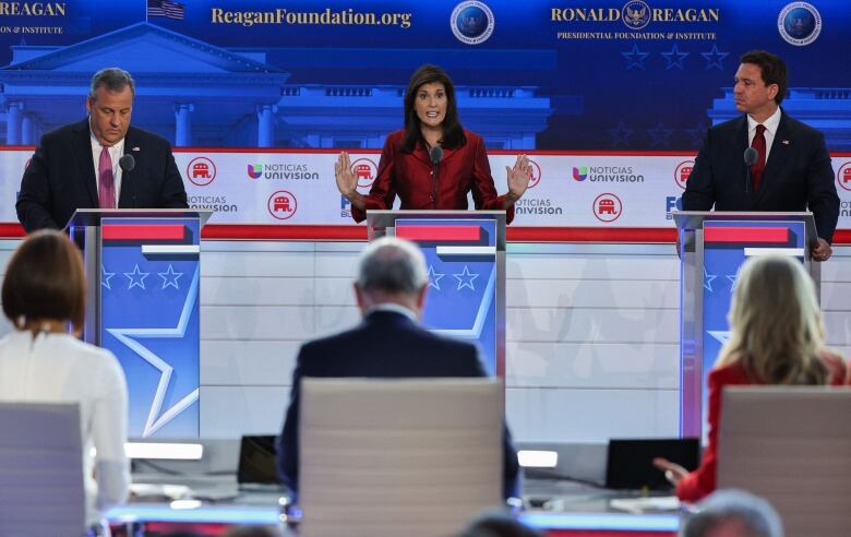 Three individuals on stage at podiums