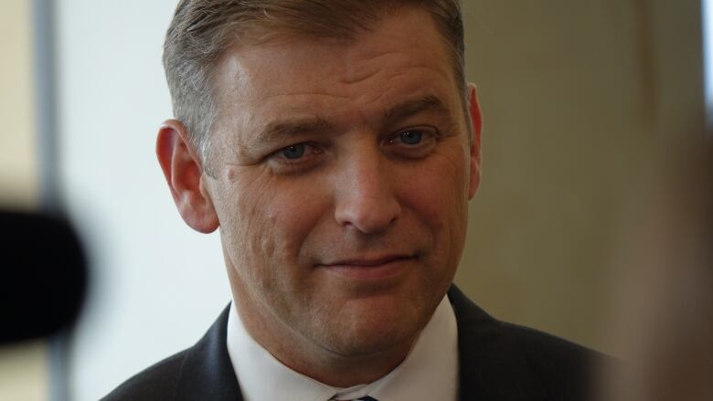 A man with a suit and tie smiles. 