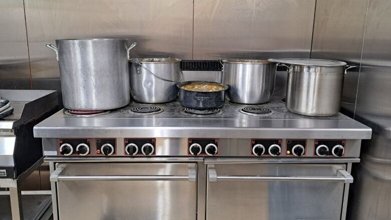 Large pots used for the Kugluktuk Meals on Wheels sit on a stove.