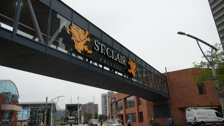 A pedestrian overpass with St. Clair College signage is shown above a street.