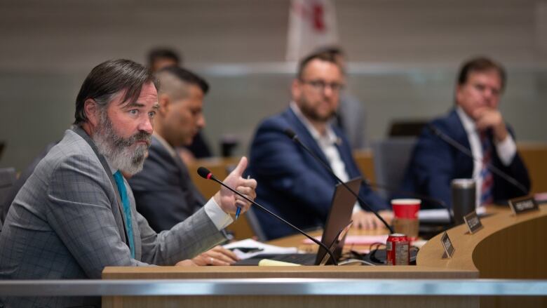 A group of city councillors at a meeting, with one in the foreground.