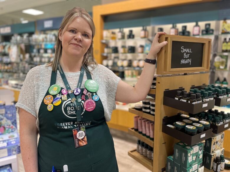 A woman leans with hear hand against a display inside a store. 