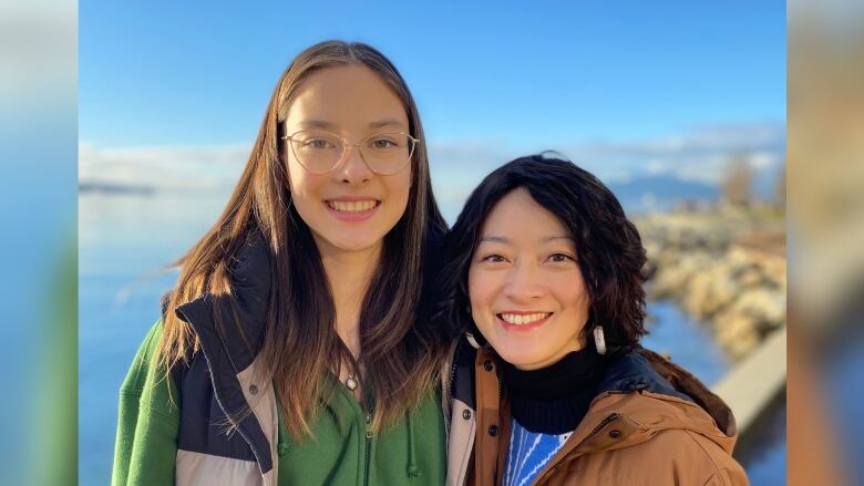 Two women stand smiling beside each other.