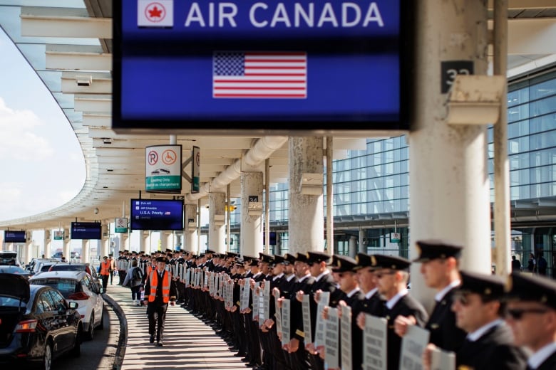 Air Canada pilots stand in a picket line.