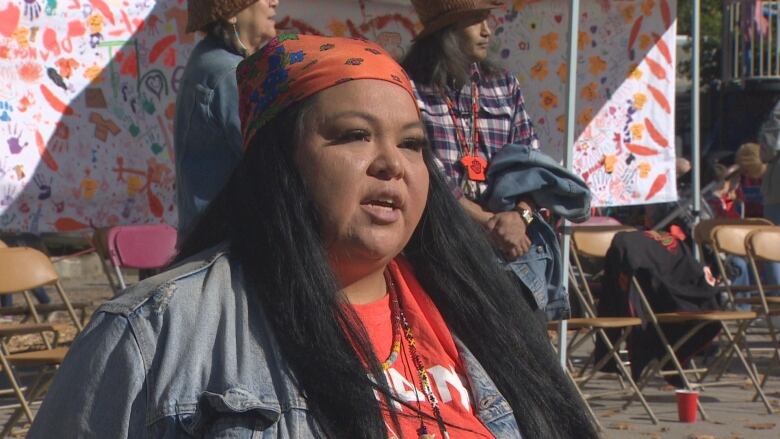 A woman in a bandana speaks to the camera.