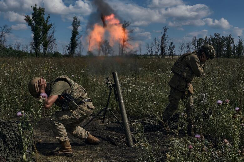 Soldiers cover their ears and turn away as they fire a mortar.