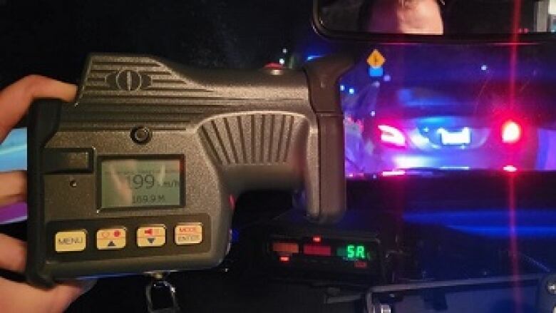 A speed detector reads 199 km/h as a car is stopped on the side of the road with flashing lights.