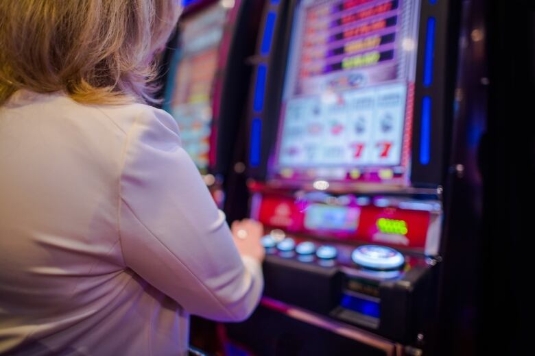 A white woman plays a slot machine.