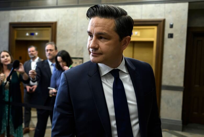 A politician looks to his right as he leaves a news conference in a legislature.