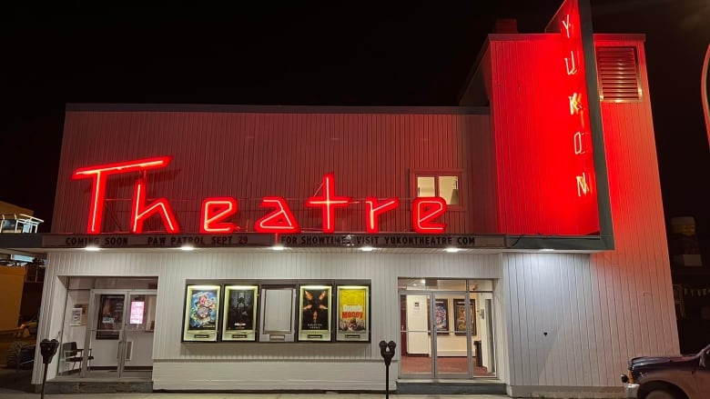 A neon sign shines bright outside of a movie theatre