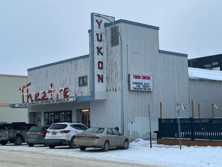 Cars parked out front of a movie theatre