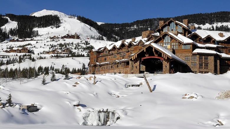 A hotel stands on a snow-covered ridge in bright sunlight.