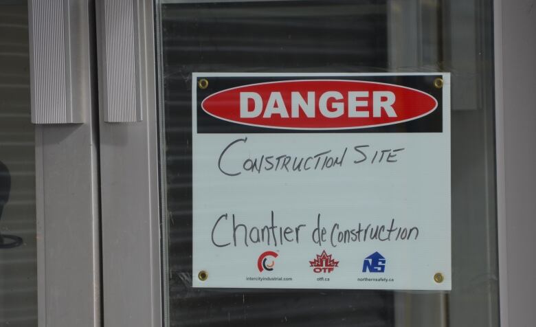 A sign on a glass door reads 'Danger: construction site'