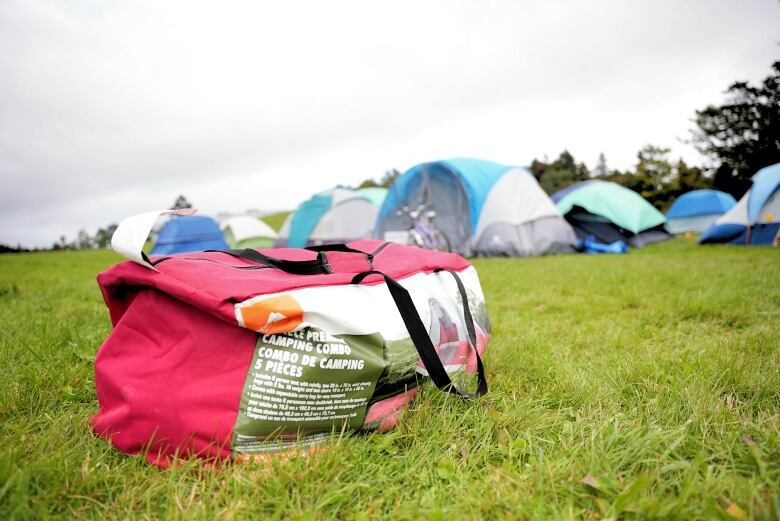 A red tent bag sitting on green grass.