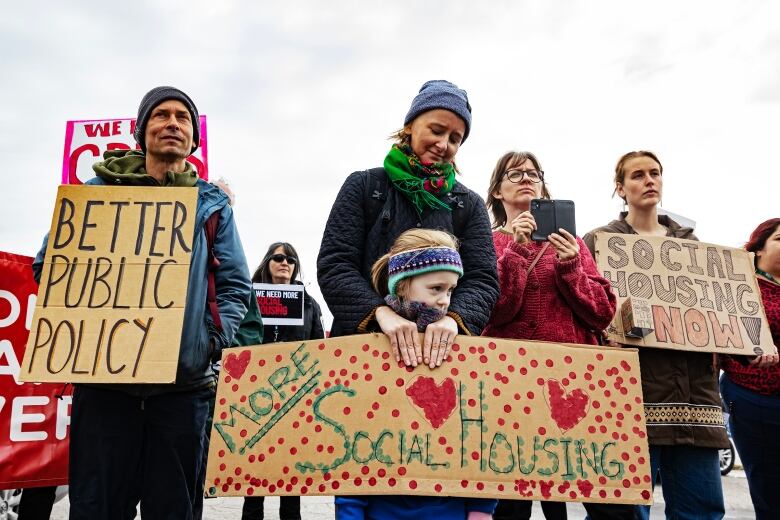 A mother and daughter hold signs at the rally outside the office of MP Dan Vandal.