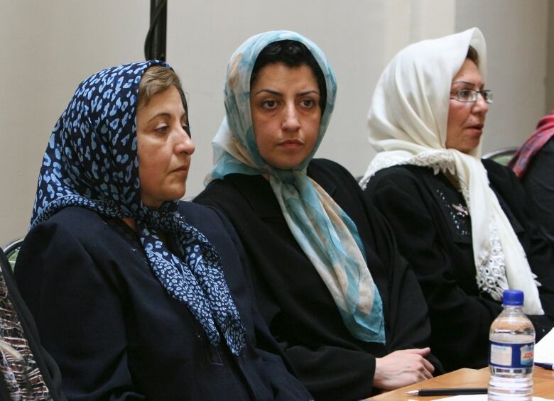 Three women are shown seated, wearing headscarves.