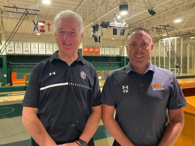 Ness Timmons and Deano Morley stand in the Sullivan Fieldhouse at CBU. Behind them is banners from the sports teams across campus.