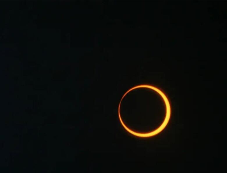 On a pitch black background, we see an orange ring that's slightly brighter on one side of the ring than the other. 