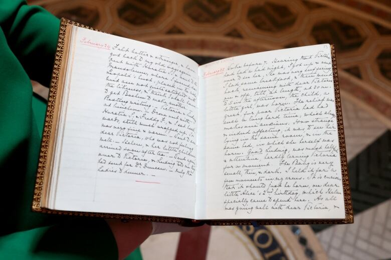 A book is held open showing handwriting on the left and right sides.