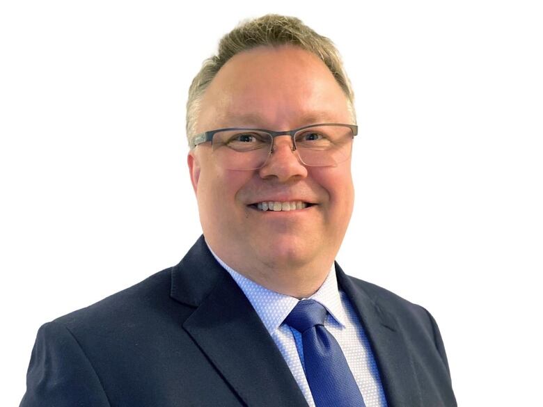 A man in a suit poses for a headshot photo. 