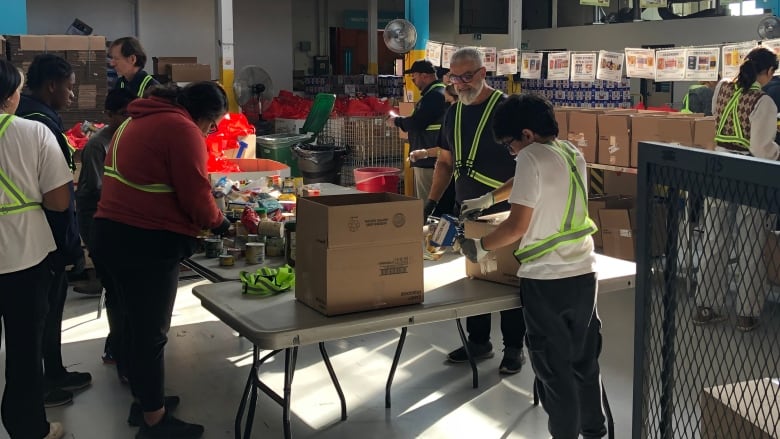 Volunteers sort and pack food in boxes.