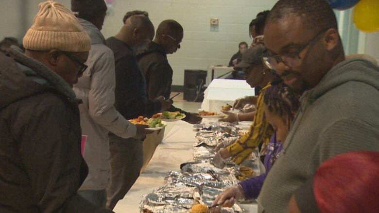 People serve food to a group of people.