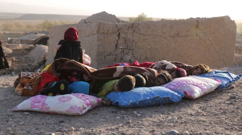 Children sleep outside after an earthquake in Afghanistan.