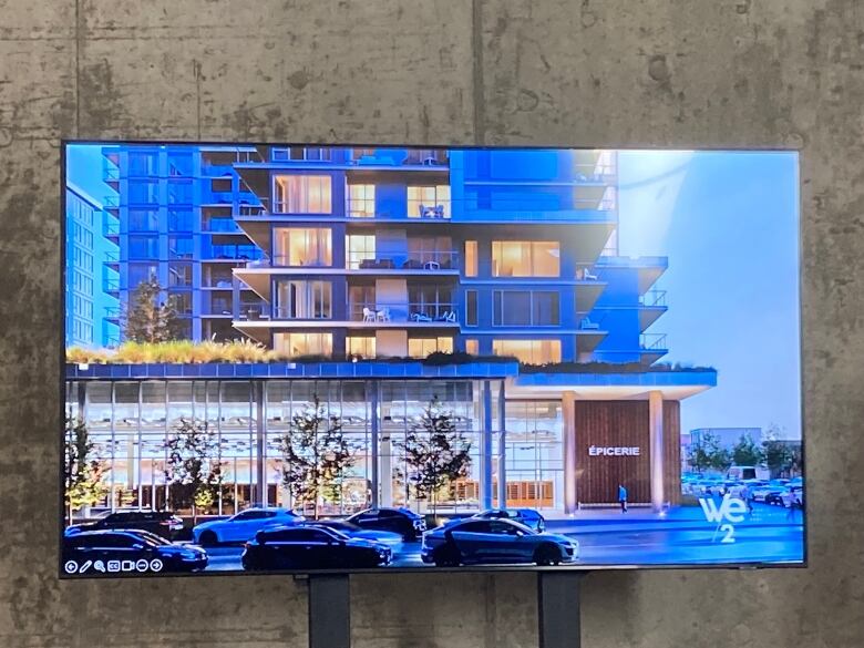 A monitor depicts the image of a finished condominium building featuring a grocery store on its ground floor. 