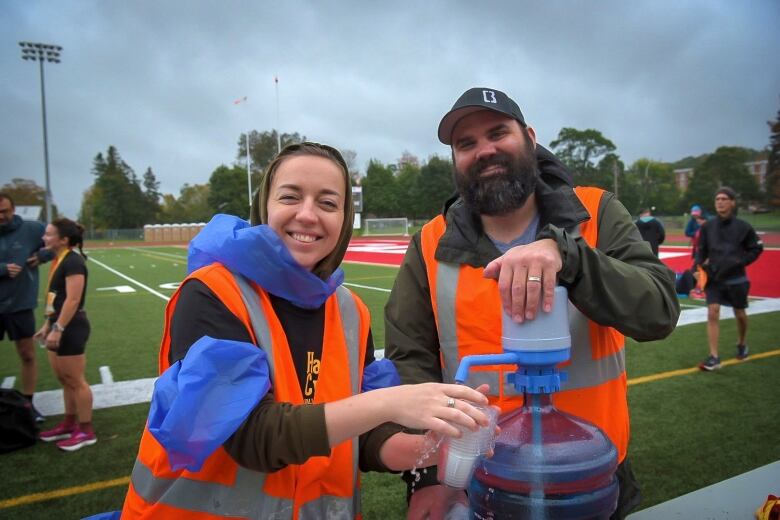 Two volunteers pump water in cups.