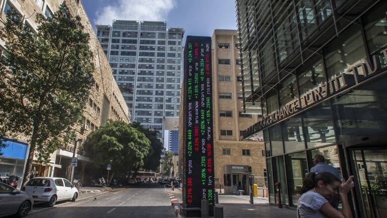 A woman is shown outside the Tel Aviv Stock Exchange building.