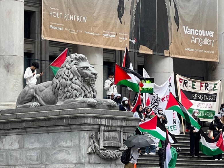 People wave Palestinian flags in front of an art gallery.