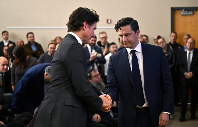 Two politicians shake hands at an event.