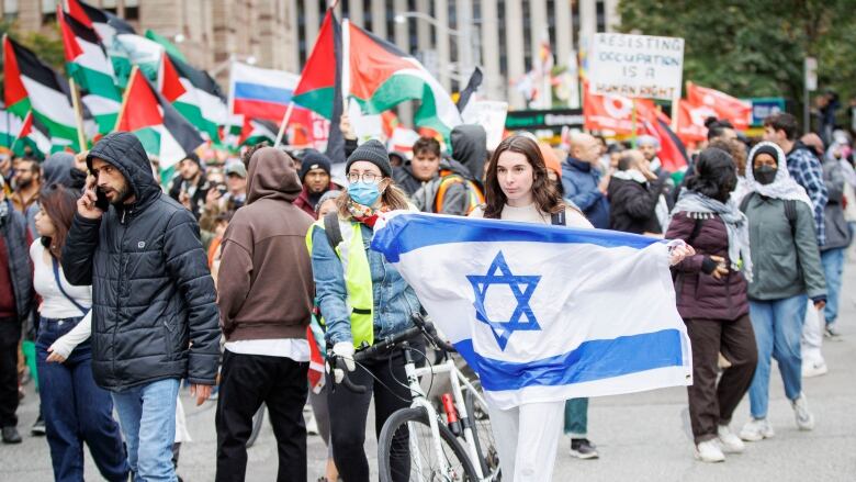 Someone holding the flag of Israel is surrounded by police during a Palestinian supporters rally in Downtown Toronto on Oct. 9, 2023.