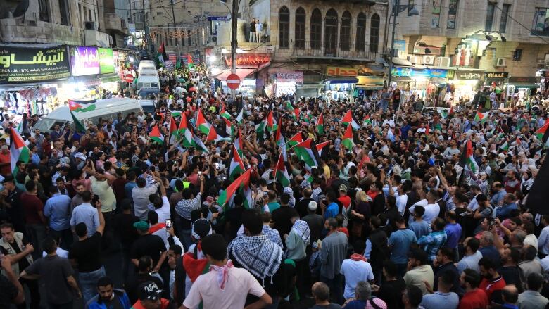 A large gathering of people in a demonstration is shown on an urban street.