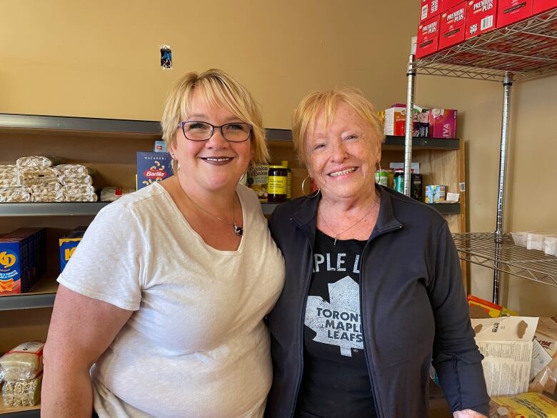 Norma Dingwell and MaryLee Steele smile near canned food inside the Montague food bank. 