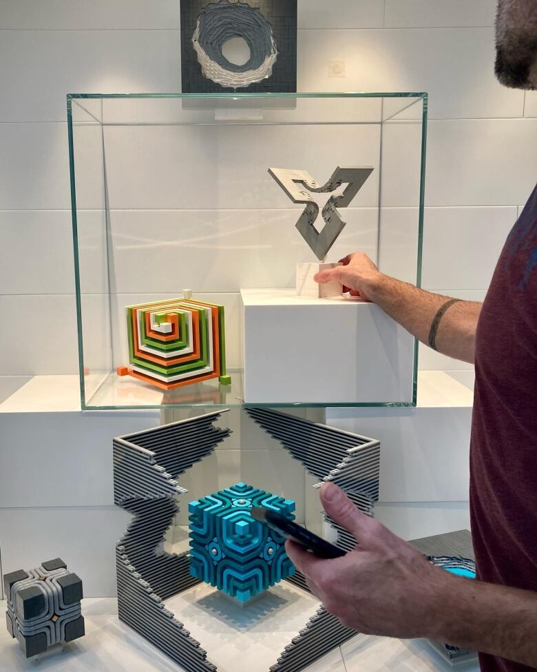 A man, just out of frame, adjusts a small lego art display.