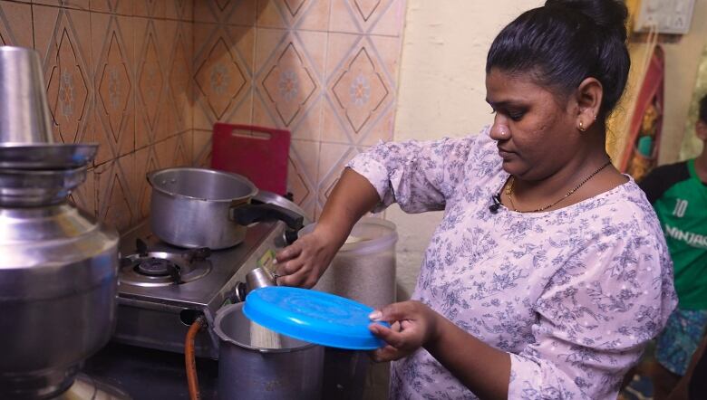 A person pours lentils into a pot on a stove.