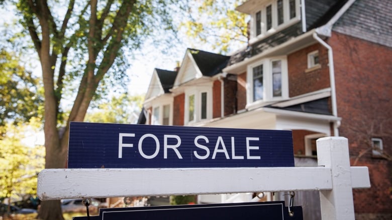 A for sale sign near a house.