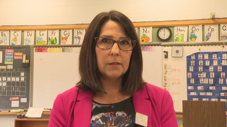 A woman in a pink blazer stands in a classroom