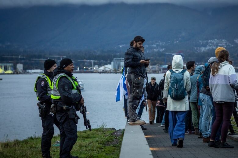 Police watch on the sidelines of a vigil in Vancouver honouring those killed in a recent terror attack in Israel.