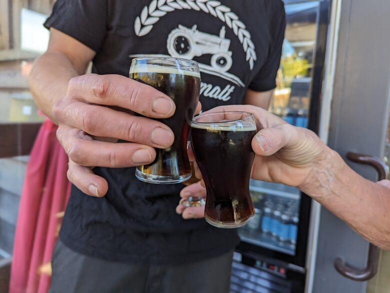 Two small glasses of beer raised to make a toast