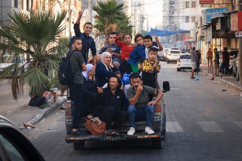 At least 11 people are jammed into the back of a small vehicle on a city street.