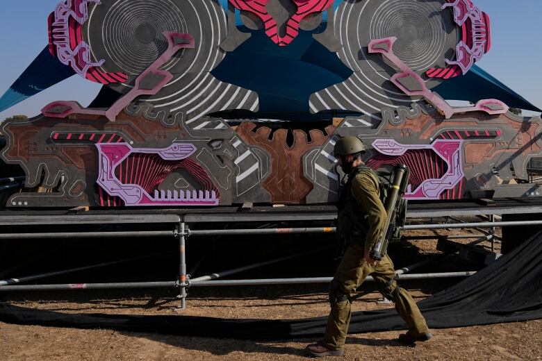 A soldier walks in front of a brightly coloured stage.