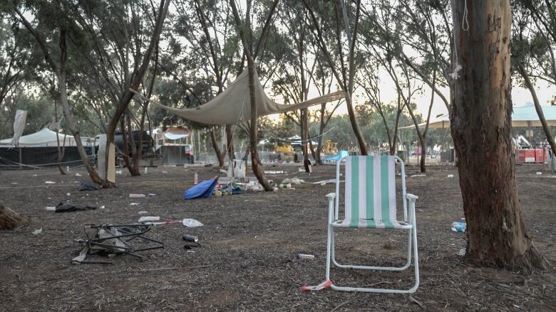 An abandoned chair and other camping equipment in a field