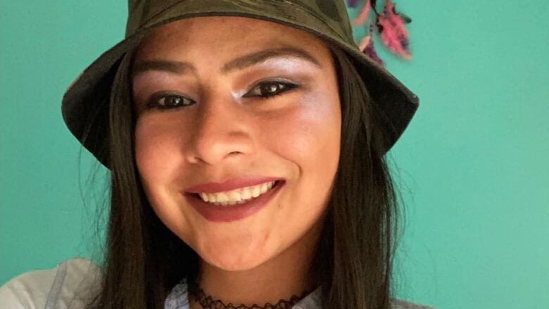 A close-up photo of a woman wearing a camouflage bucket hat is shown.